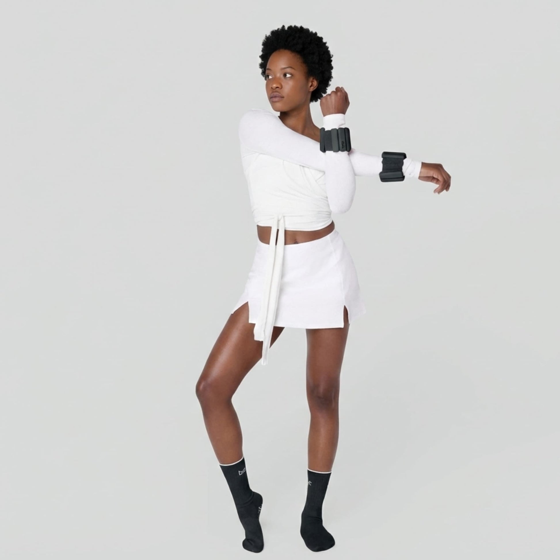 Femme s'étirant les bras pendant sa séance de fitness à domicile, avec les poids pour poignets Neo-Sweat pour intensifier l'effort.