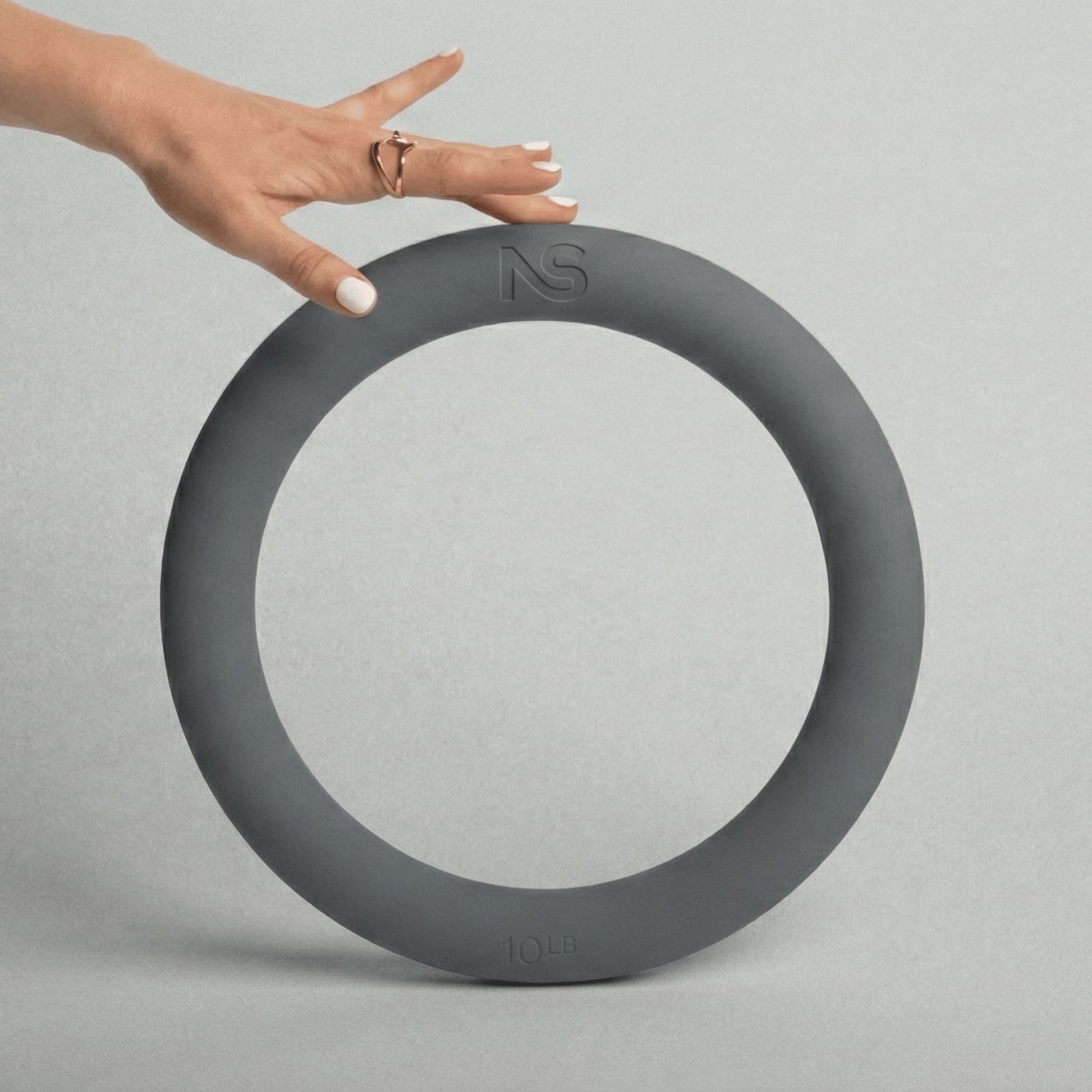 Main posée en équilibre sur le bord supérieur d'un anneau de musculation gris de 4,5 kg, permettant d'apprécier ses dimensions et sa prise en main.