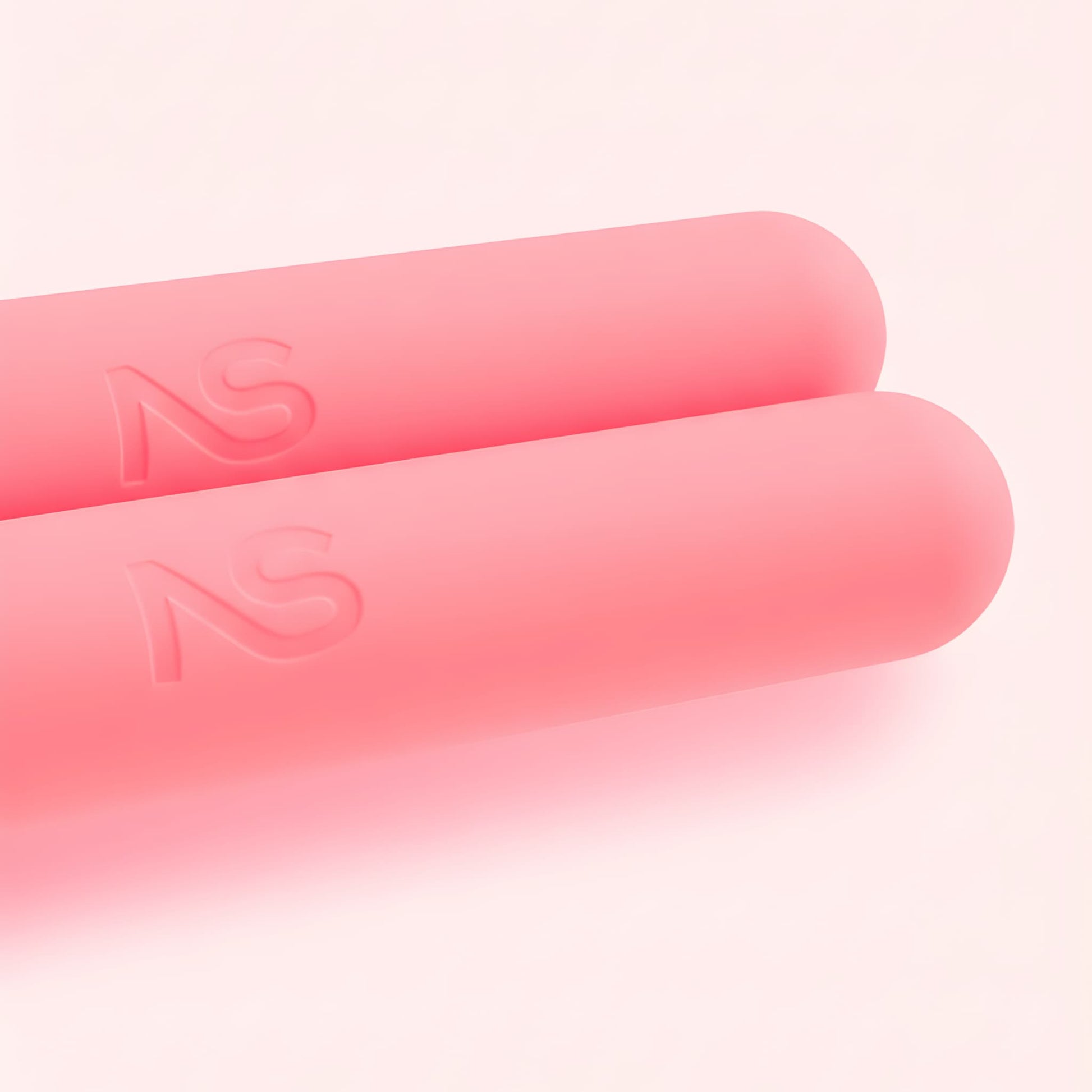 Gros plan sur la texture douce et le logo NS gravé sur les haltères ergonomiques roses Neo Sculpt Bars.