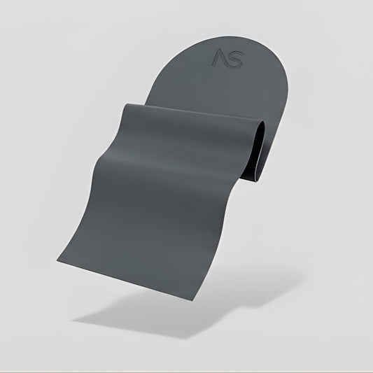 Tapis de sport gris foncé souple avec bord supérieur arrondi, capturé en train de se dérouler en lévitation sur un fond clair.